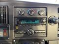 Dashboard of a 2019 Chevrolet Express featuring climate controls a radio display and various buttons and knobs for audio settings