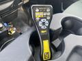 A black and yellow control remote with buttons for operating equipment, placed in a cup holder of a vehicle.