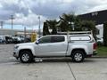 A 2018 Chevrolet Colorado pickup truck in silver with a utility cap on the bed parked beside palm trees