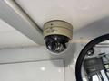 A dome security camera mounted on the ceiling of a vehicle with the name SEON visible on its front