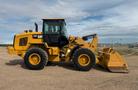 A 2016 CAT 938M wheeled loader with a yellow body and large front bucket is positioned on a gravel surface