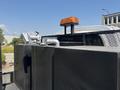 A 2005 GMC C7500 Topkick with a black body featuring a mounted silver valve and a flashing orange light on top