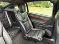 Interior view of a 2020 Tesla Model X featuring black leather seats with a wood finish accent on the door panel