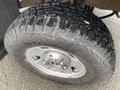 Close-up of a rugged tire on a 2005 Ford F-350 SD featuring deep treads and a shiny metal wheel rim