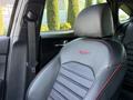 A black leather car seat with red stitching featuring the Kia logo on the headrest