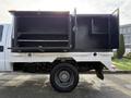 A 2015 Ford F-550 with an open utility bed featuring black storage compartments and shelves on one side