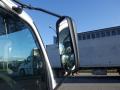 A 2015 Hino 195 truck with a prominent side mirror reflecting the scene nearby