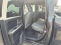 A 2015 RAM 1500 with an open driver's side door showing the interior and back seat area featuring gray upholstery and a spacious layout