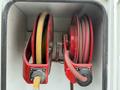 Two red hose reels mounted inside a compartment with yellow and red hoses visibly coiled on each reel