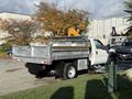 A 2008 Ford F-550 dump truck with a silver bed and a yellow hydraulic arm attached on the back