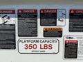 2008 Ford F-550 with safety warning signs and capacity label on the side indicating a platform capacity of 350 lbs without liner