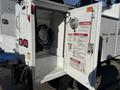 A 2009 Ford F-550 service truck with an open compartment revealing a tool storage area and safety warning labels on the inside door