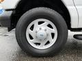 A close-up of a silver wheel from a 2006 Ford Econoline featuring alloy spokes and a rugged tire design