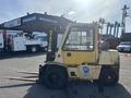 A 1993 Hyster H80XL forklift with an orange and white color scheme featuring a lifted mast and two long forks extended forward