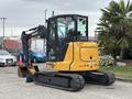 A 2017 John Deere 50G compact excavator with a yellow and black body and tracks is positioned with its digging arm extended forward