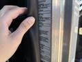 A hand holding a metal pole next to a vehicle identification label showing specifications for a 2020 Peterbilt 330 truck