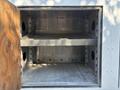A metal storage compartment with an open wooden door revealing two empty shelves inside