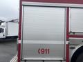 A silver and red emergency vehicle with roll-up doors and the number 911 displayed prominently on the side