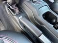 The interior of a 2021 Jeep Wrangler showing the gear shifter and handbrake with red stitching on black leather seats
