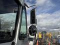 A 2017 Freightliner MT45 with a large side mirror and a smaller convex mirror attached to the driver's side, showing the truck's sleek design and reflective surfaces