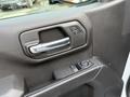 Close-up of the interior door panel of a 2024 Chevrolet Silverado 1500 showing the door handle and control buttons for windows and locks