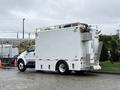 A white 2011 Ford F-650 truck with a large cargo area and multiple compartments on the side