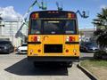 A yellow 2011 Freightliner B2 school bus viewed from the rear showing its brake lights and large rear windows