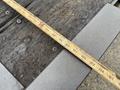 A measuring tape laid across a wooden surface showing measurements with the tape extending past the edges of the wood