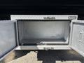 An empty silver storage compartment made of diamond-plate metal with two opened doors located on a vehicle