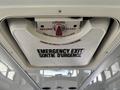 Ceiling-mounted emergency exit hatch with a red handle and bilingual instructions for opening in English and French