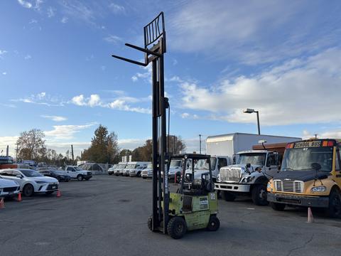 A green 2000 Clark GPS 15 forklift with a tall vertical mast and two forks extending from the front