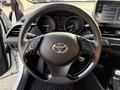Steering wheel of a 2021 Toyota C-HR featuring control buttons and the Toyota emblem in the center