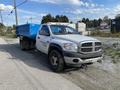 A gray 2009 Dodge Ram 5500 truck with a blue dump bed attached parked on a gravel surface