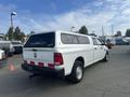 A white 2012 RAM 2500 with a truck bed cover parked in a lot showing its rear and side profiles