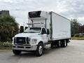 A 2019 Ford F-750 truck with a white trailer and a refrigeration unit on top parked on a paved surface