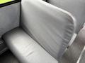 A gray upholstered seat with a simple, textured design typically found in a bus or vehicle interior