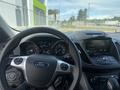 Interior view of a 2014 Ford Escape showing the steering wheel dashboard and central console with controls and display