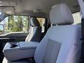 A gray interior of a 2014 Ford F-250 SD showing the driver's seat and armrest with a console in between