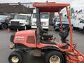A 2015 Kubota F3990 lawn mower with a red cab and black seat visible from the side with large tires and a cutting deck attached