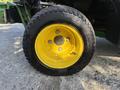 Close-up of a yellow wheel from a 2021 John Deere 1575 with a black tire showing tread details and metal rim components