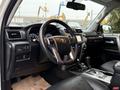 The interior of a 2018 Toyota 4Runner featuring a black steering wheel with controls a dashboard display and leather seats