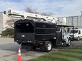 A 2012 International DuraStar 4300 bucket truck with a black body and a raised aerial lift on top positioned on a paved area