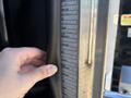 A hand holding a rubber seal or door frame next to a measurement chart on the side of a 2020 Peterbilt 330 truck showing tire and maintenance specifications