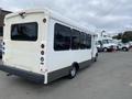 A white 2020 Chevrolet Express bus with large windows and a gray lower body is parked, showing its rear and side without any visible branding on the back