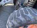 A close-up of a tire from a 2015 Bobcat 5600 showing a rugged tread pattern and part of the vehicle's frame and suspension components