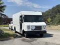 A white 2012 Ford Econoline truck with a large delivery box design and a front loading area parked on a street