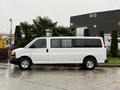A white 2021 Chevrolet Express van with large windows and chrome wheels parked on a wet surface