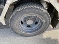 A close-up view of a tire on a 2002 Ford F-550 showing a rugged tread pattern and a large steel wheel rim