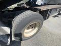 Close-up of a tire from a 1997 Freightliner FL70 showing a worn tread pattern and rusted rim with visible dirt on the surface