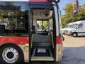 A red and white 2016 Grande West Vicinity bus with an open door revealing the driver's seating area and controls